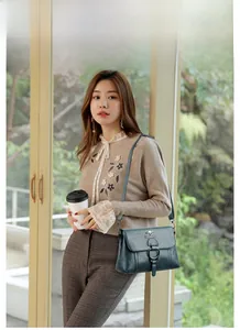 Detail of dark green PU leather shoulder bag featuring metal ring and kangaroo hardware