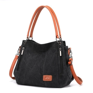 Black canvas tote bag with brown leather straps and stylish decorative zippers