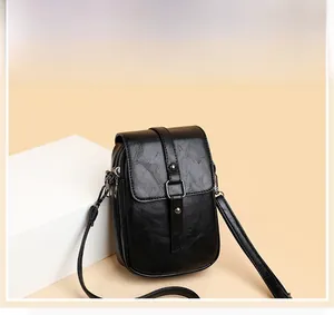 Detail of black PU leather crossbody bag featuring fine lychee grain and metal buckle