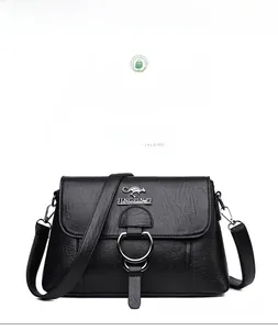 Detailed view of black pebbled leather crossbody bag with metallic logo and ring buckle