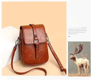 Macro shot of brown PU leather crossbody bag with metallic buckle and fine grain texture