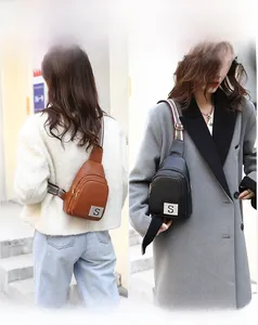 Detail of leather crossbody chest bags in brown and black with stylish striped straps