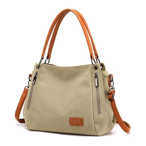 Khaki canvas tote bag with brown leather handles and side zip pockets for daily use