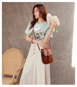 Brown PU leather crossbody bag with flap closure shown on a model in a casual setting