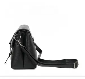 Detailed side view of black PU leather shoulder bag with lychee texture and silver hardware