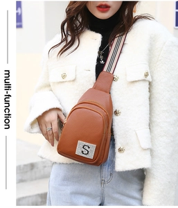 Close-up of brown litchi grain leather chest bag with crystal S logo and striped strap