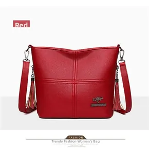 Detail of red textured leather bucket bag with kangaroo logo and side tassels