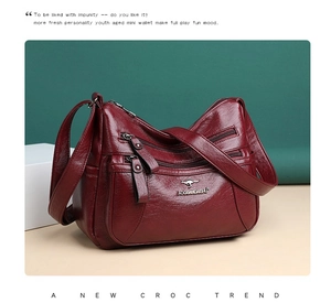Dettaglio borsa a tracolla rosso vino con pelle morbida e tasche multiple con cerniera