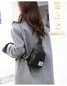 Detail of black pebbled PU chest bag featuring a rhinestone S logo and striped strap