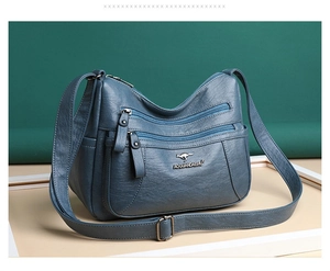 Dettaglio borsa a tracolla blu scuro in morbida pelle con vari scomparti con zip
