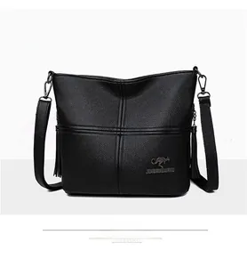 Close-up of black PU leather crossbody bag with tassel detail and lychee texture