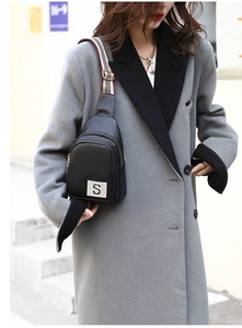Close-up of black litchi pattern PU chest bag with sparkling metal S and striped strap