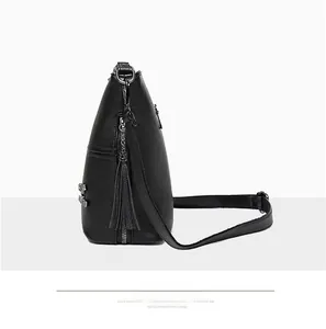 Side view of black pebble leather crossbody bag with fringe tassel and silver hardware