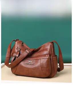Dettaglio borsa in pelle marrone con scomparti multipli a zip e logo metallico decorativo