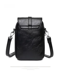 Close-up of a vertical black PU leather crossbody bag with lychee texture and buckle strap