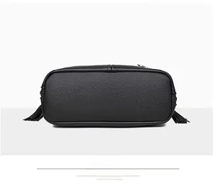 Bottom view of black pebble leather crossbody bag with stitching and side tassels