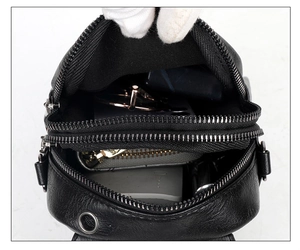 Detail of black pebbled PU leather crossbody bag with dual zipper compartments showing storage