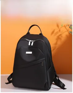 Détail d'un sac à dos en tissu Oxford noir avec fermetures éclair argentées sur fond orange