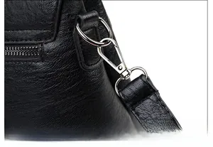 Close-up of black litchi pattern leather texture with shiny silver metal hook