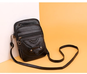 Macro detail of black litchi grain faux leather phone bag with multiple zipper pockets