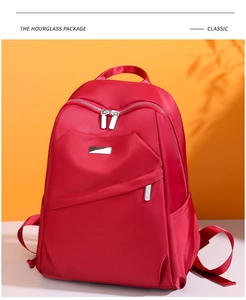 Vue de face d'un sac à dos rouge en tissu oxford avec fermetures éclair sur fond orange