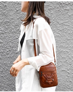 Detailed view of brown PU leather crossbody bag featuring woven texture and metal studs