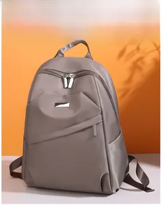 Détail du sac à dos en nylon marron montrant la texture lisse et la fermeture éclair en métal
