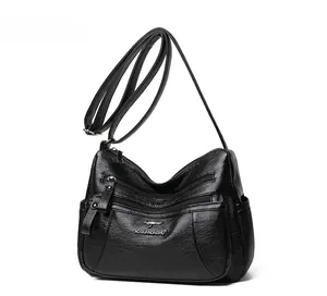 Dettaglio borsa a tracolla in pelle nera con tasche multiple a cerniera e logo metallico