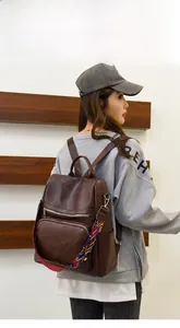 Detailed back view of dark brown PU leather backpack with colorful woven strap on model