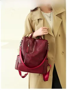 Burgundy faux leather backpack worn with beige trench coat, showing side view and red straps