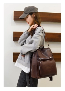 Detail view of large dark brown PU leather backpack featuring printed shoulder strap