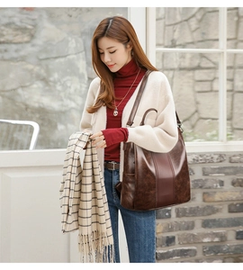 Detail of dark brown leather backpack showing side pockets and vintage stitching