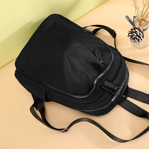 Minimalist black nylon backpack with multiple compartments on a warm color background