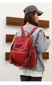 Detail of red faux leather backpack with colorful geometric woven strap on model
