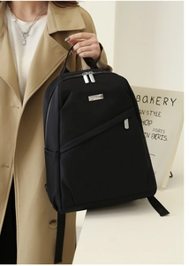 Détail du sac à dos en nylon noir imperméable avec logo en métal et poche zippée