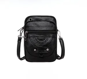Detail of black pebbled faux leather crossbody bag with triple zipper and woven texture