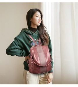 Side view of dark red PU leather backpack on model showing adjustable straps and texture