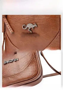 Detail of brown litchi pattern leather bag with silver kangaroo logo and stitching