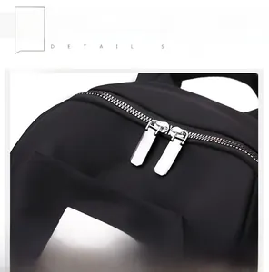 Détail des fermetures éclair en métal argenté sur un sac à dos en tissu oxford noir
