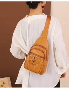 Close-up of vintage brown PU leather sling bag with woven details and triple zipper layers