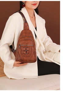 Detail of vintage brown PU leather sling bag with woven accents and multi-zipper pockets