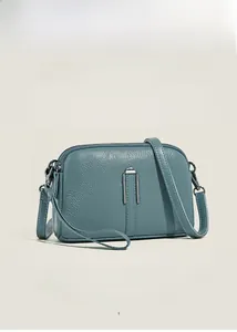 Detail view of grey-blue leather handbag with litchi texture and U-shaped metal decor