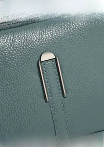 Macro detail of turquoise lychee grain leather with fine double stitching and metal hardware