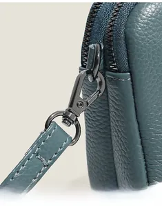 Detailed close-up of blue lychee grain leather texture and metallic swivel hook on bag