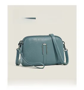 Detail of blue pebbled leather shoulder bag with silver U-shaped metal hardware and strap