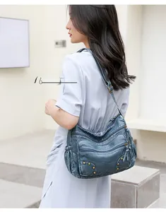 Close-up of a vintage dark blue PU leather shoulder bag with multi-zipper pockets