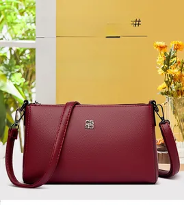 Detailed close-up of wine red litchi texture leather crossbody bag with metal accent