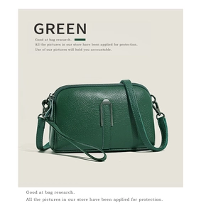 Detail of green litchi texture leather handbag featuring a polished silver U-shaped metal buckle