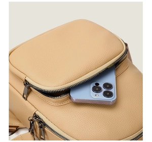 Detail of lychee textured beige backpack showing front zipper pocket with smartphone storage