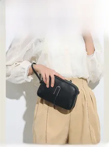 Detailed view of black litchi leather handbag with silver U-shaped metal decoration